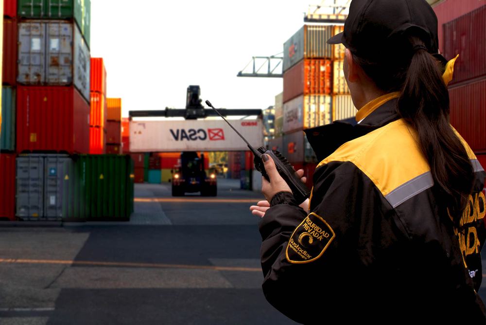 Guarda de Custodiar con radio vigilando un patio de contenedores